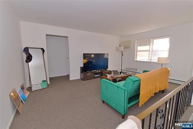 a living room with furniture a flat screen tv and a window