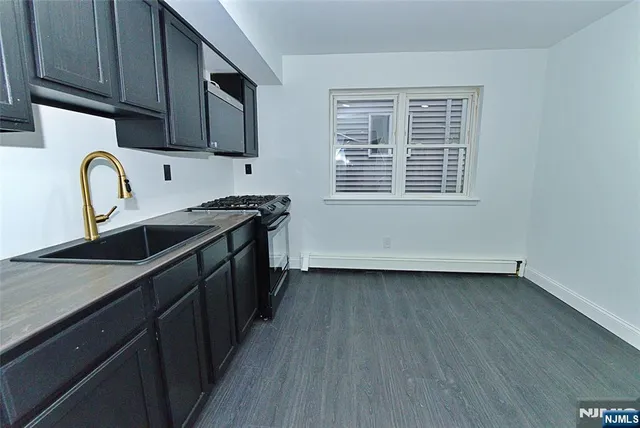 a kitchen with stainless steel appliances granite countertop a sink a stove a refrigerator cabinets and wooden floor