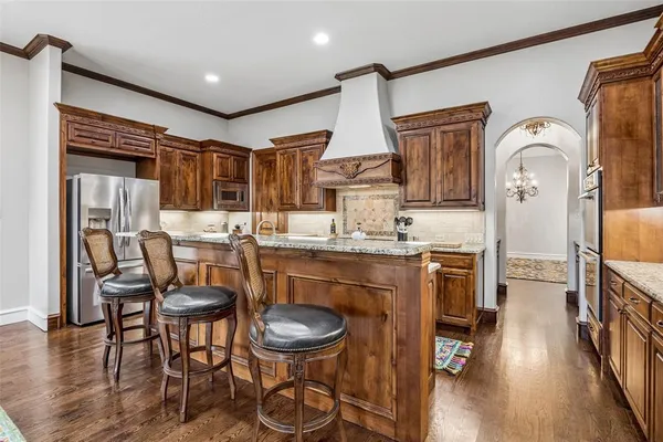a kitchen with stainless steel appliances kitchen island granite countertop a table chairs in it and wooden floors