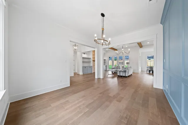 a view of a livingroom with wooden floor a refrigerator chandelier and a window