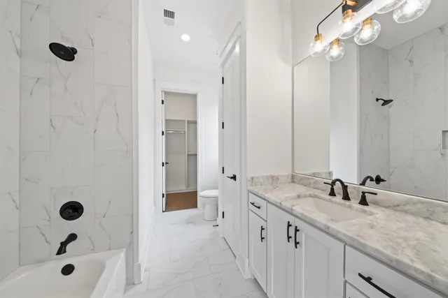 a bathroom with a granite countertop sink a mirror a shower and a bathtub