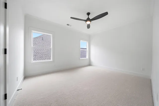 a view of a livingroom with a ceiling fan & windows