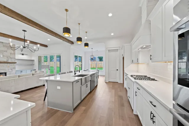 a large white kitchen with stainless steel appliances granite countertop a lot of counter space and wooden floors