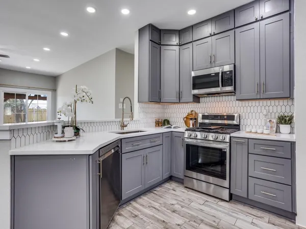 a kitchen with stainless steel appliances granite countertop a stove a sink and a microwave