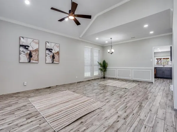 a view of an empty room with wooden floor and a ceiling fan