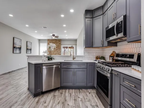 a kitchen with stainless steel appliances granite countertop a stove a sink and a microwave
