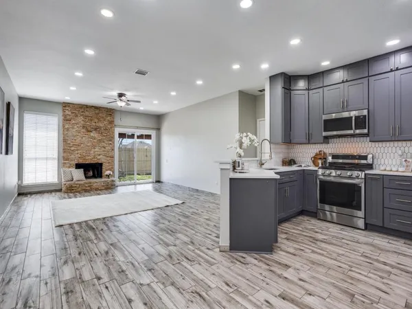 a large kitchen with kitchen island a sink dishwasher stove and a refrigerator with wooden floor