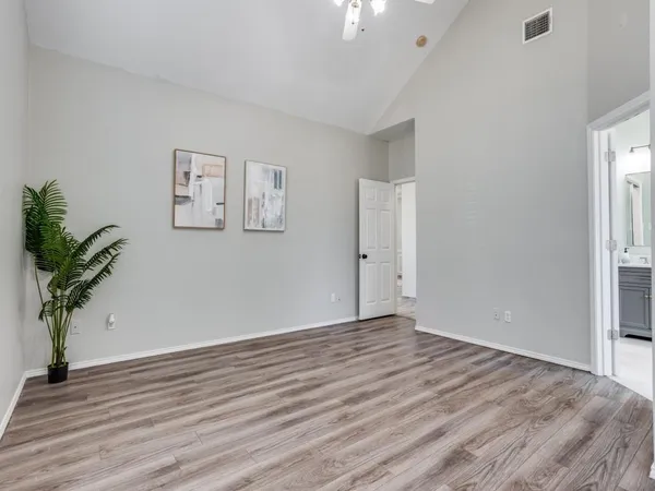 a view of an empty room with wooden floor and a potted plant