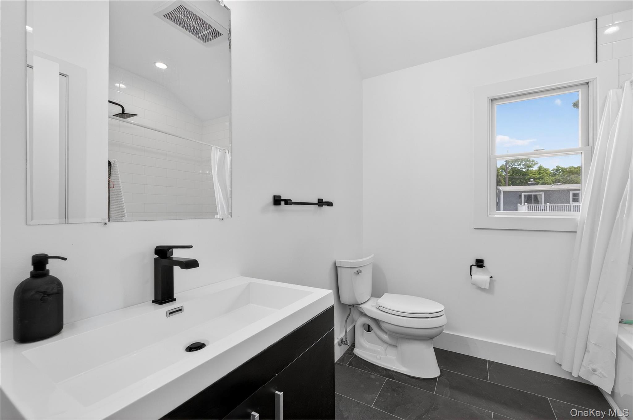 534 Riverside Avenue Massapequa, NY 11758 - Photo 21 of 28 a bathroom with a sink a toilet and a mirror