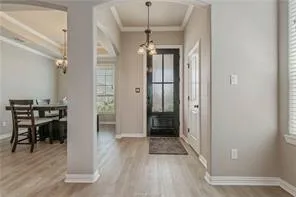 a view of a hallway with wooden floor table and chairs