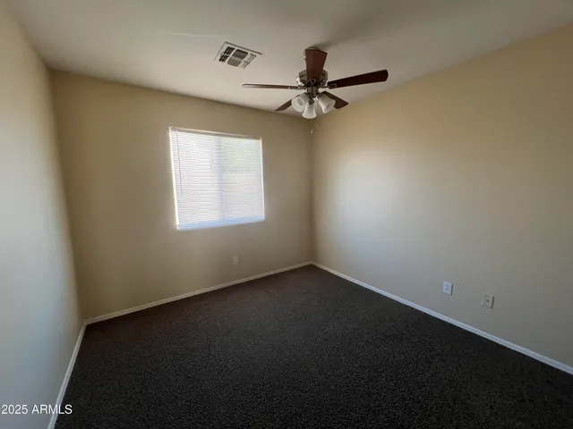 an empty room with a window and a fan