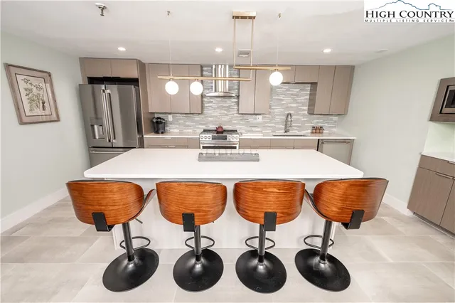 a kitchen with stainless steel appliances granite countertop a sink a stove and chairs