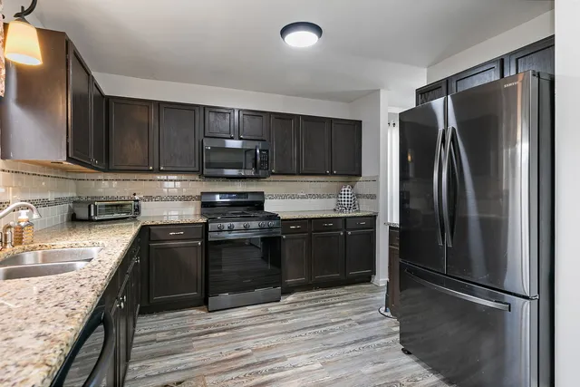 a kitchen with stainless steel appliances granite countertop a refrigerator stove and sink