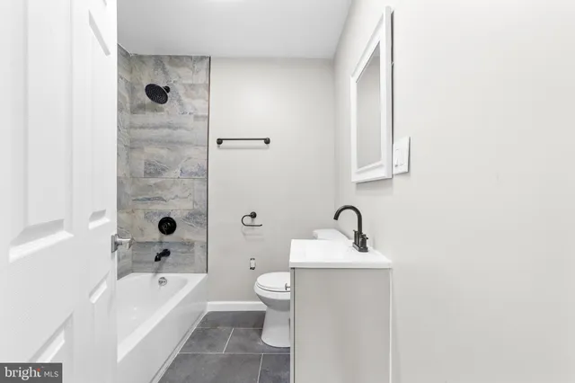 a bathroom with a granite countertop sink a toilet and bathtub