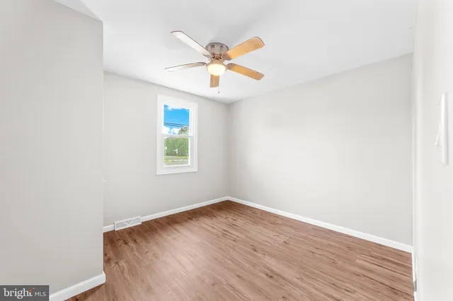 an empty room with a window and a ceiling fan
