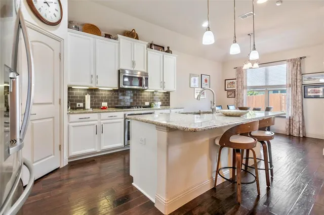 a kitchen with stainless steel appliances granite countertop a white cabinets and a stove top oven