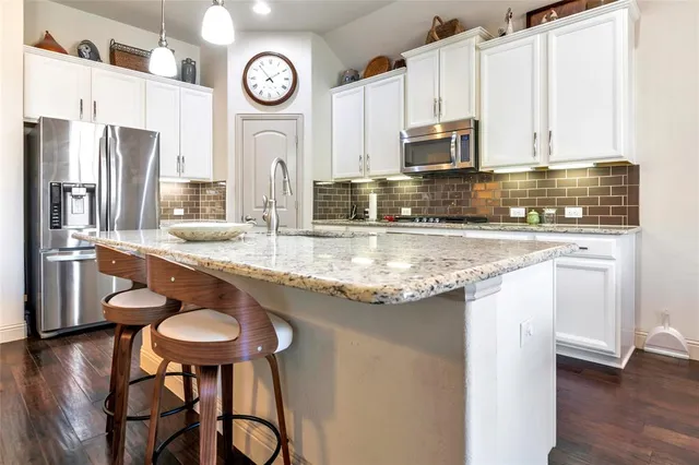a kitchen with stainless steel appliances granite countertop a sink a stove and a refrigerator