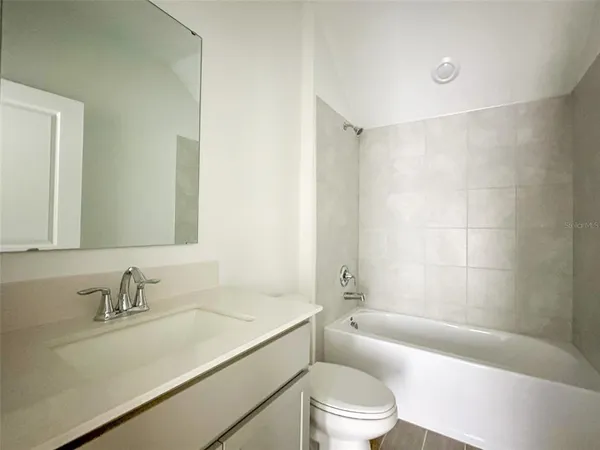 a bathroom with a granite countertop sink a toilet a mirror a bathtub and shower