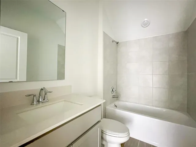 a bathroom with a granite countertop sink a toilet a mirror a bathtub and shower