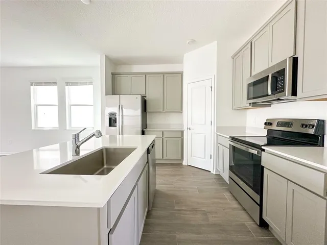 a kitchen with stainless steel appliances granite countertop a sink and a refrigerator