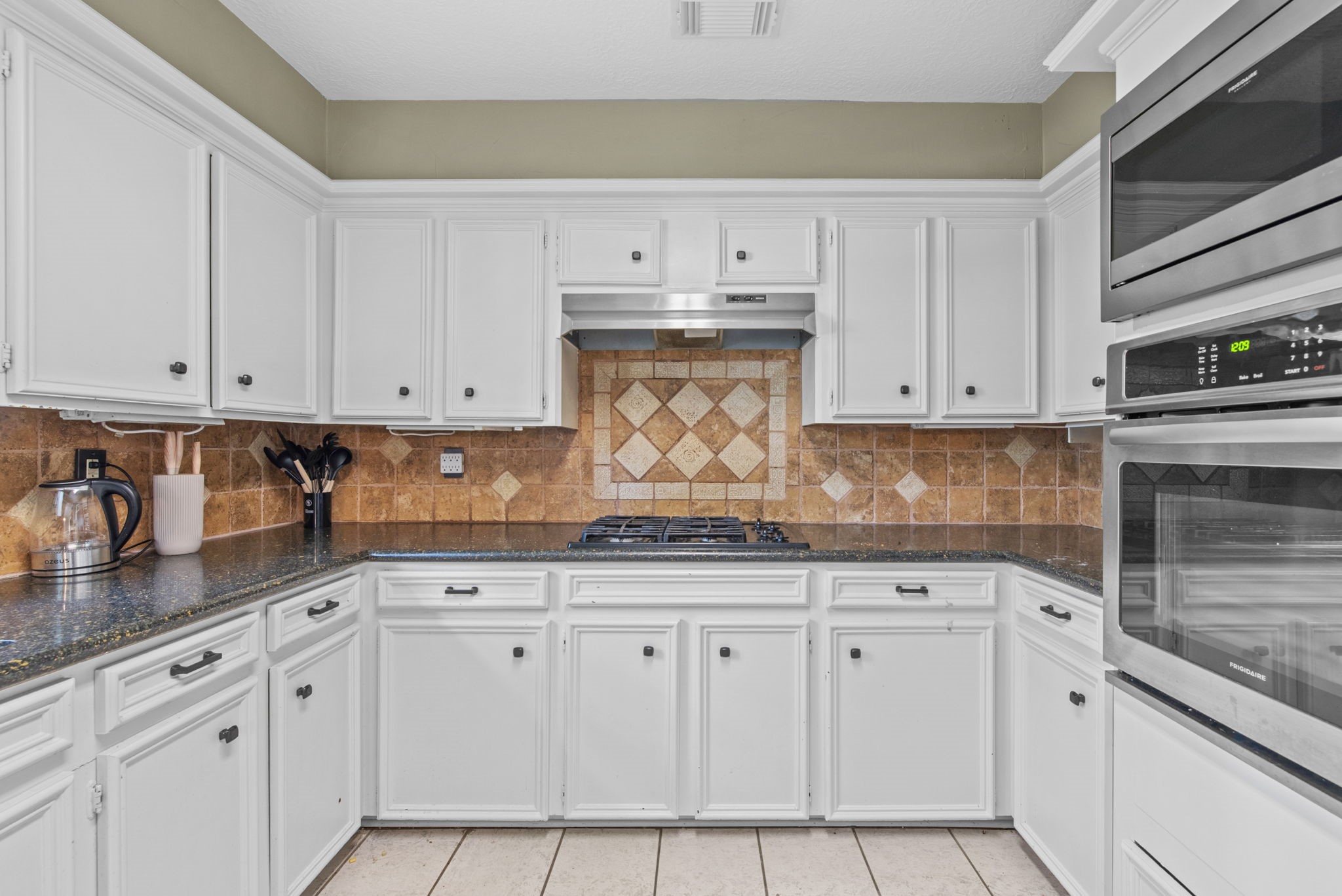 5507 Glenmere Lane Spring, TX 77379 - Photo 15 of 37 a kitchen with granite countertop white cabinets and stainless steel appliances