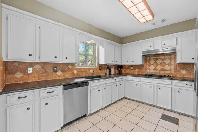 a kitchen with granite countertop white cabinets white appliances and sink