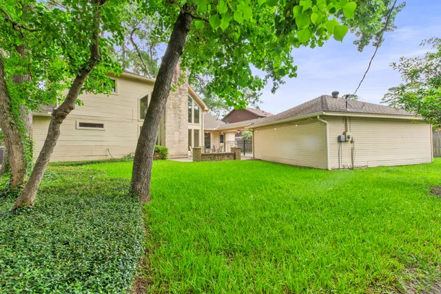 a view of a house with a yard and a large tree