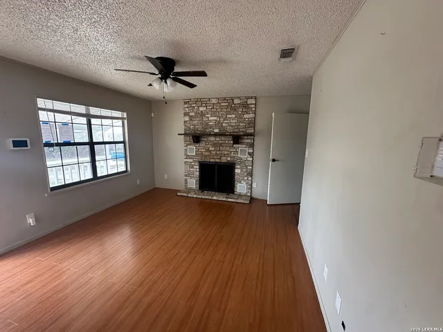 an empty room with wooden floor fireplace and windows