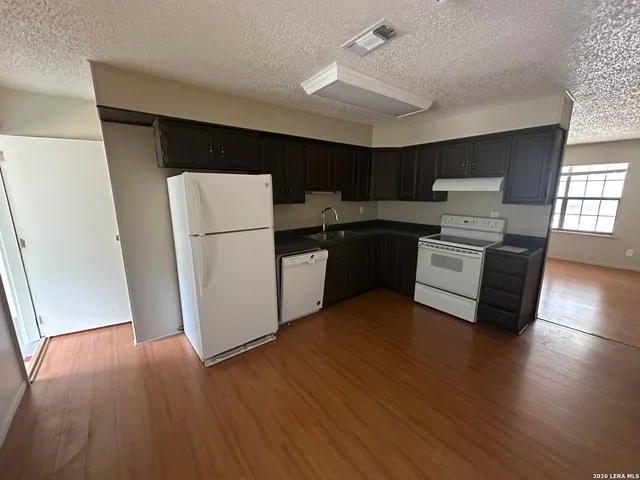 a kitchen with a refrigerator a stove top oven a sink and wooden floor