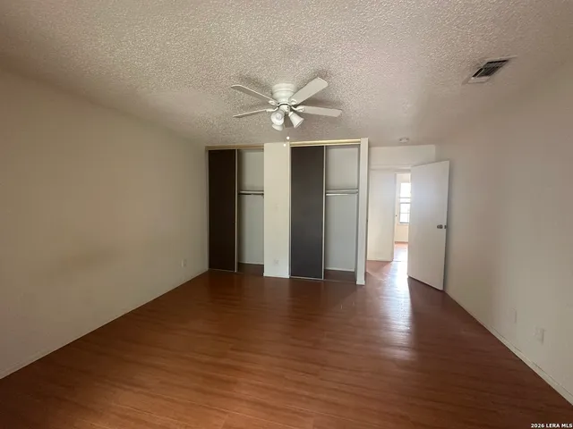 an empty room with wooden floor and a ceiling fan