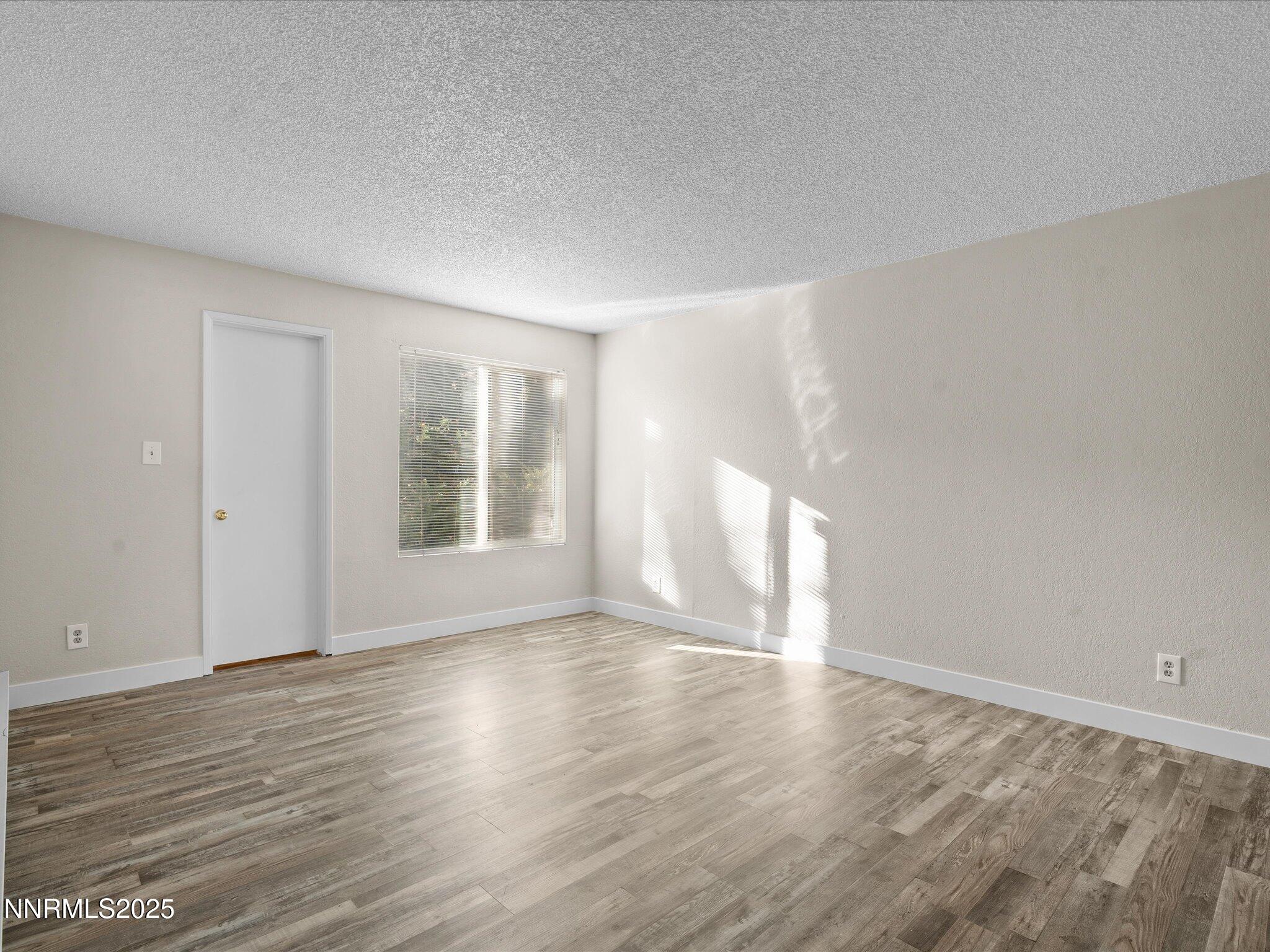 3935 Clear Acre Lane, Unit 215 Reno, NV 89512 - Photo 22 of 31 a view of an empty room with wooden floor and a window