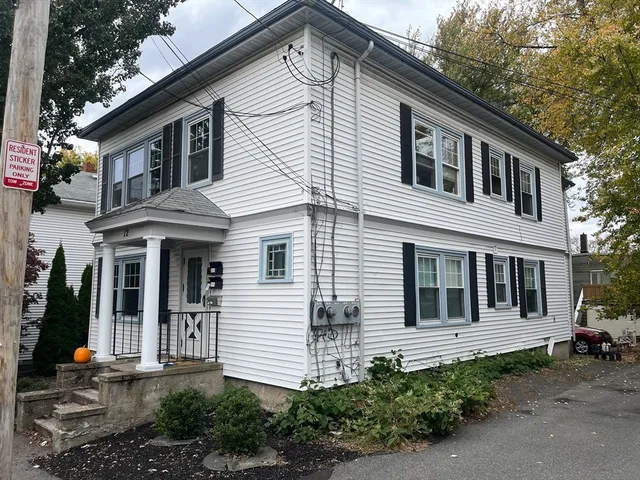 a view of a white house with large windows and plants