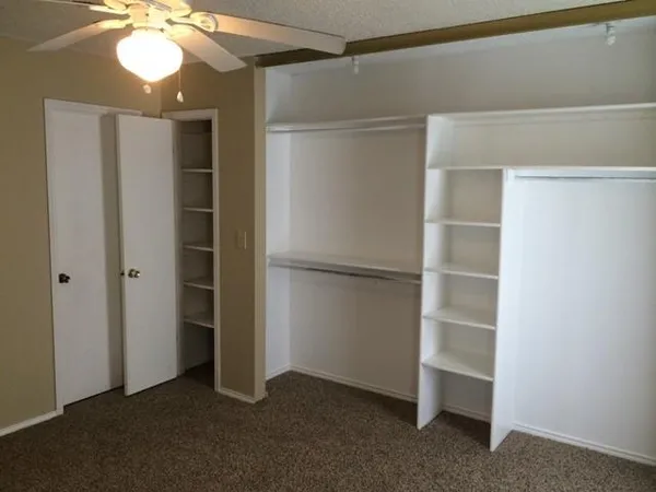 a view of an empty room with a cabinet and a ceiling fan