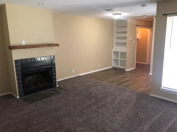 an empty room with windows and fireplace
