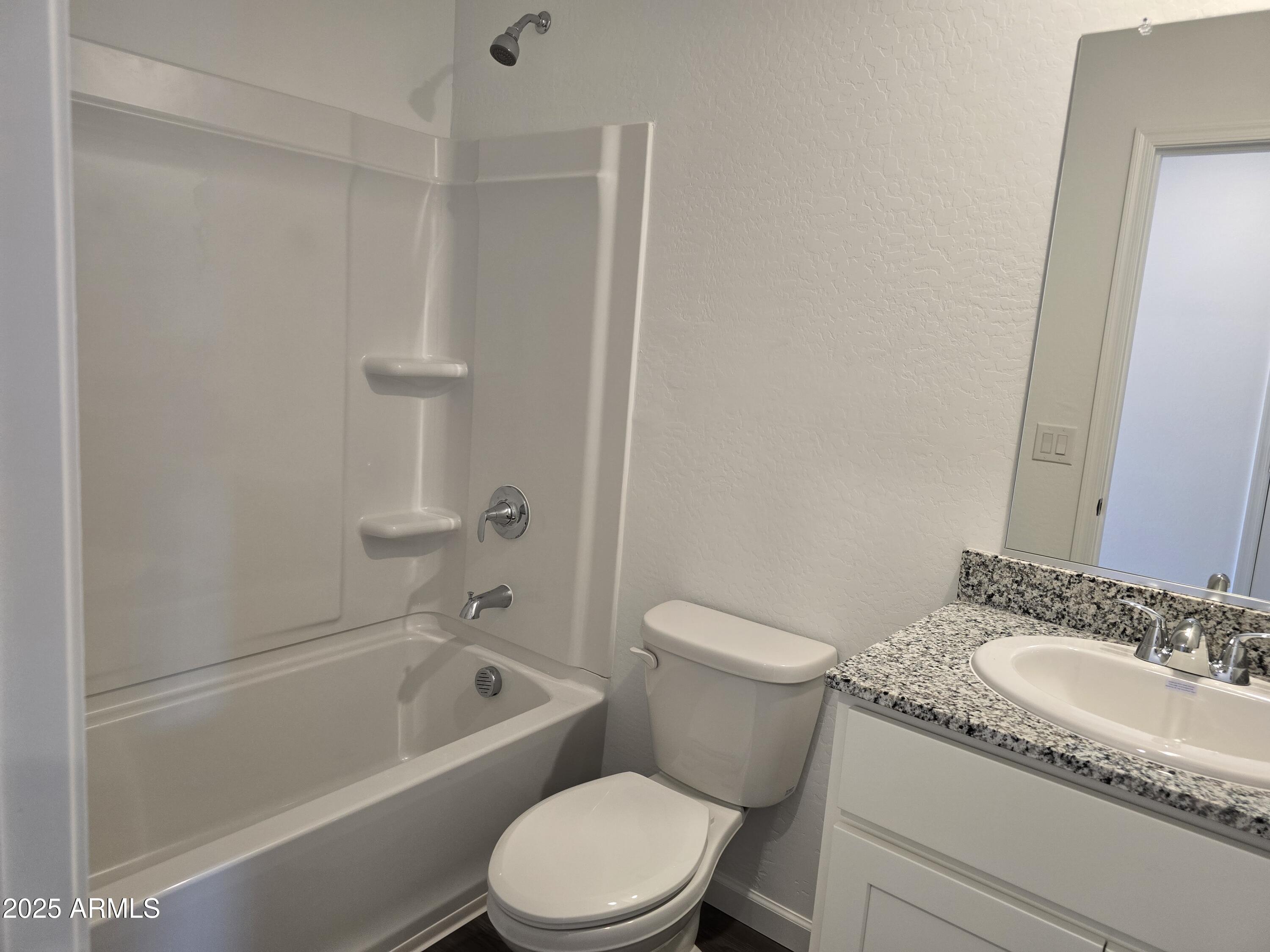 729 Dylan Court Wickenburg, AZ 85390 - Photo 3 of 14 a bathroom with a granite countertop toilet a sink and a bathtub