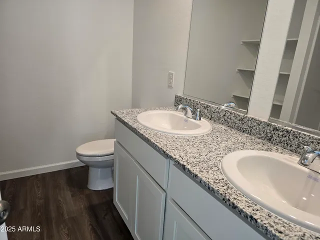 a bathroom with a granite countertop sink a toilet and a mirror