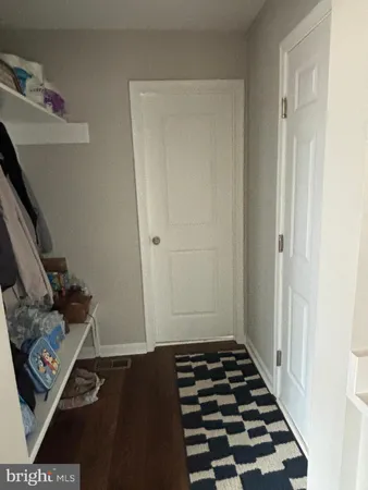 a walk in closet with wooden floor