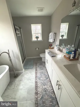 a spacious bathroom with a double vanity sink a toilet and a mirror