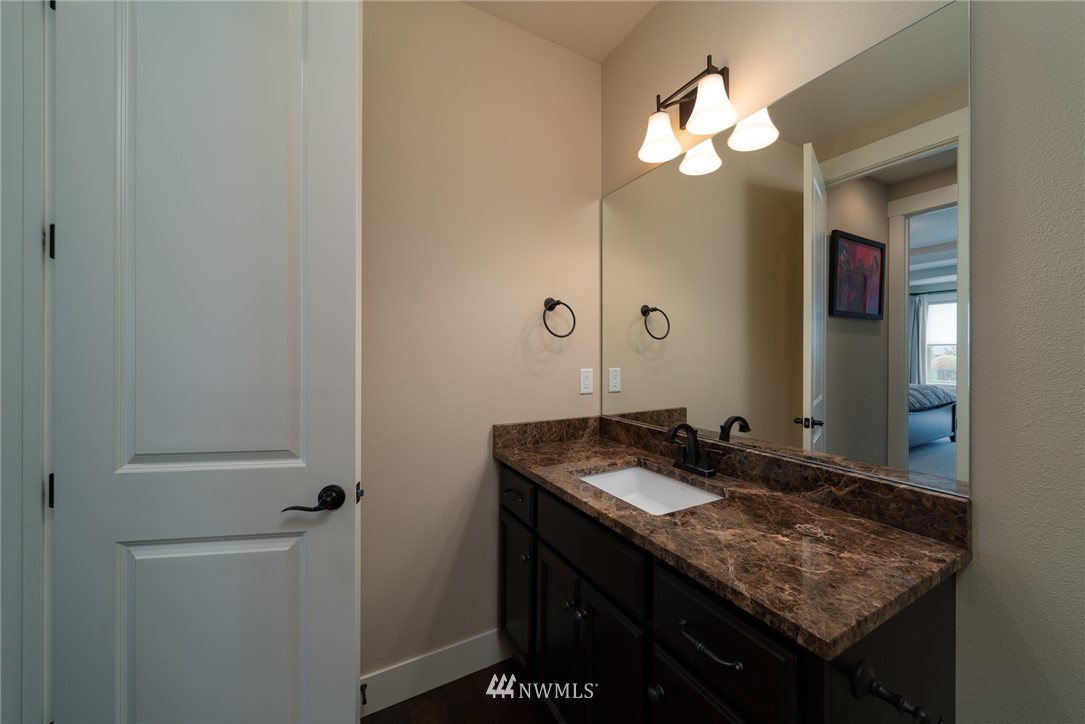 17409 Northeast 30th Court Ridgefield, WA 98642 - Photo 14 of 32 a bathroom with a granite countertop sink a light fixture and a mirror