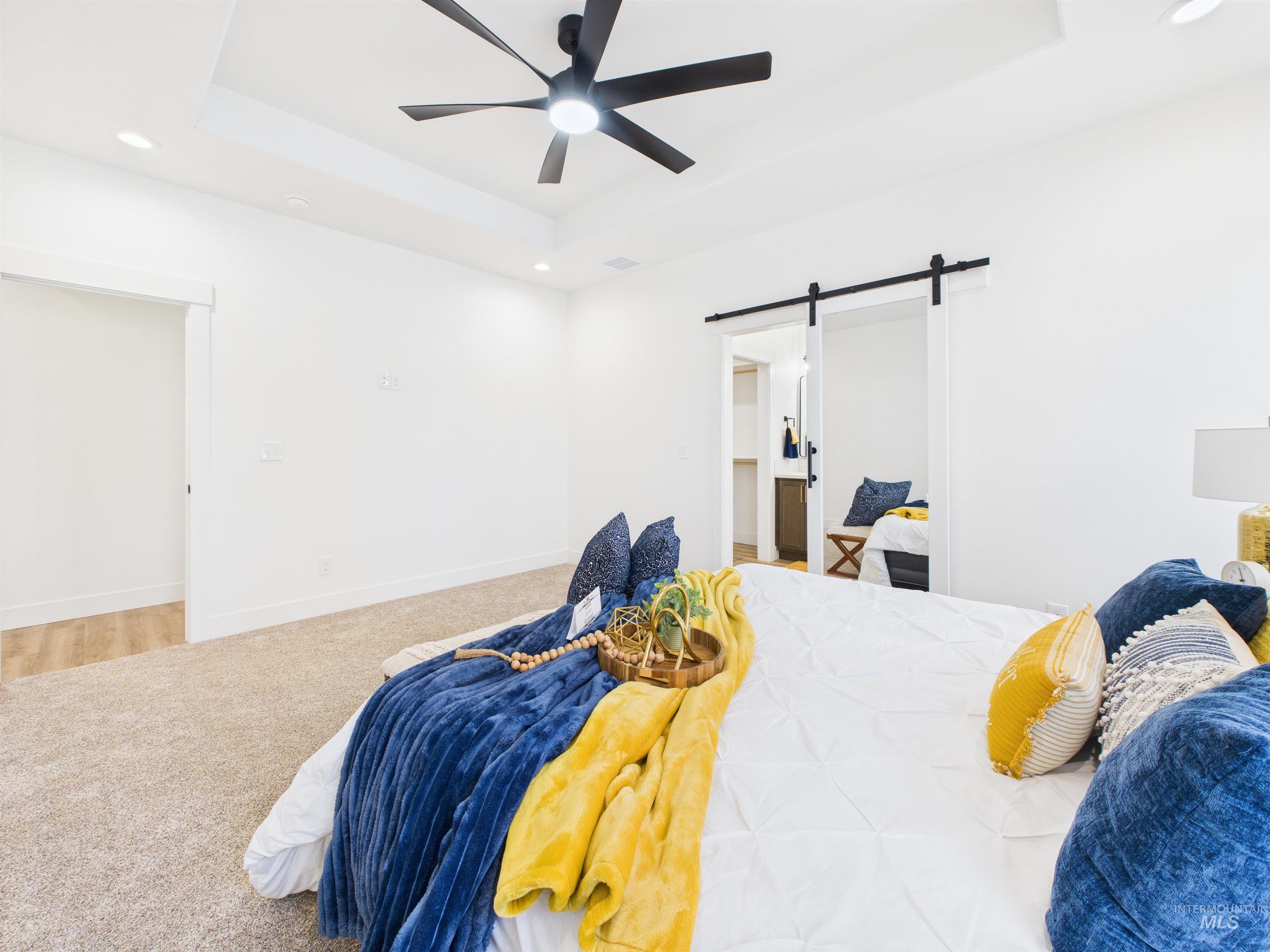1216 Bronze Drive Rupert, ID 83350 - Photo 13 of 28 Bedroom featuring a barn door, recessed lighting, a tray ceiling, ceiling fan, and carpet floors