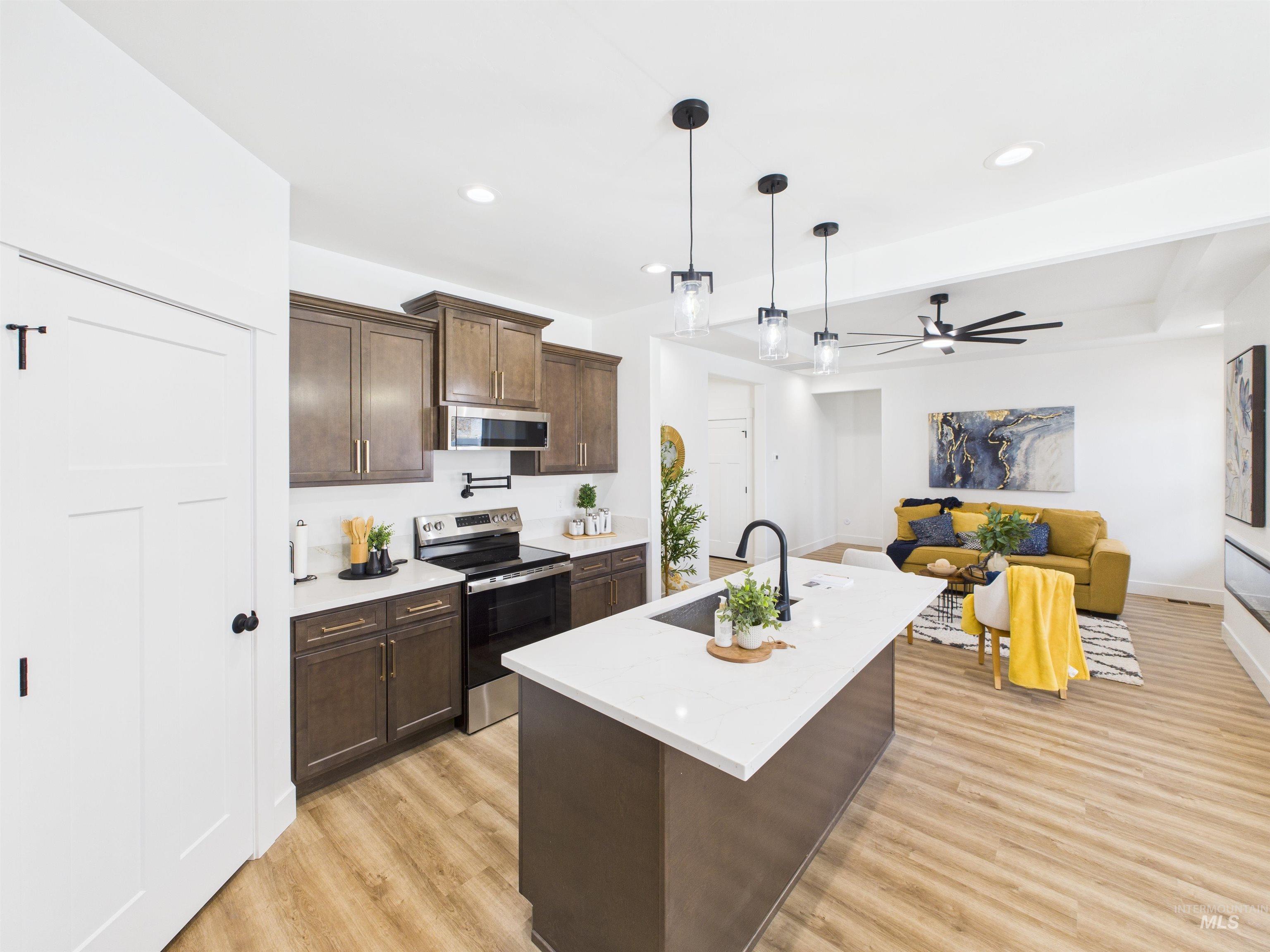 1216 Bronze Drive Rupert, ID 83350 - Photo 7 of 28 Kitchen with dark brown cabinets, stainless steel appliances, a kitchen island with sink, hanging light fixtures, and recessed lighting
