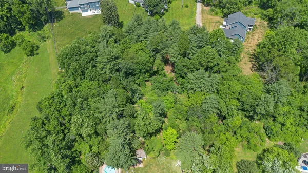an aerial view of residential house with outdoor space and trees all around