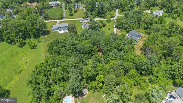 an aerial view of residential house with outdoor space and trees all around