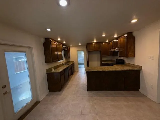 a view of empty room with wooden floor and kitchen view