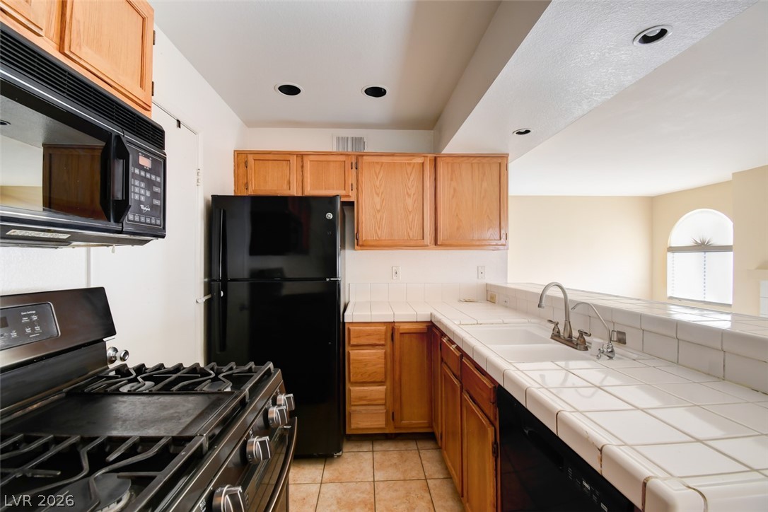 7570 West Flamingo Road, Unit 119 Las Vegas, NV 89147 - Photo 7 of 15 A well-appointed kitchen features black appliances, light wood cabinetry, and a double basin sink.