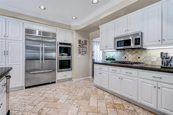 a kitchen with stainless steel appliances granite countertop a refrigerator and a stove top oven