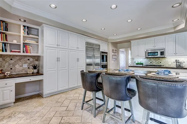 a kitchen with kitchen island a stove a sink a refrigerator and a dining table with wooden cabinet