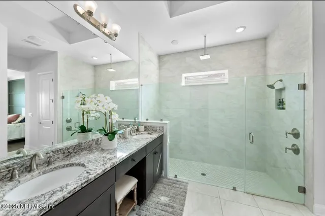 a bathroom with a granite countertop sink a large mirror and shower
