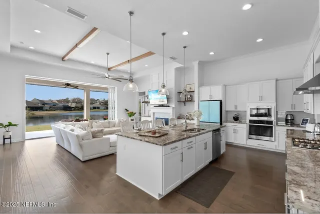 a large kitchen with stainless steel appliances kitchen island granite countertop a stove and a view of living room