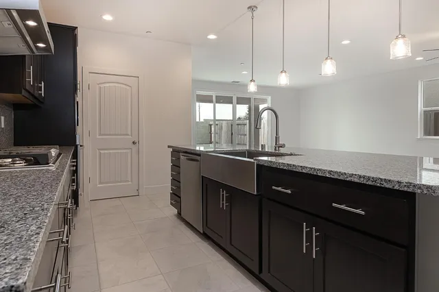 a kitchen with granite countertop a sink stove and cabinets